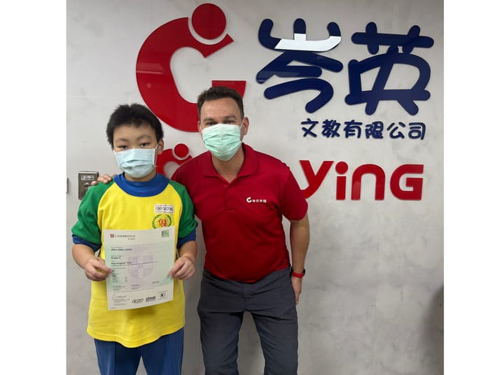 Pioneers 領航班學生 Raymond 持劍橋 Key for Schools 英語證書,與外籍教師合影,慶祝考試成功。